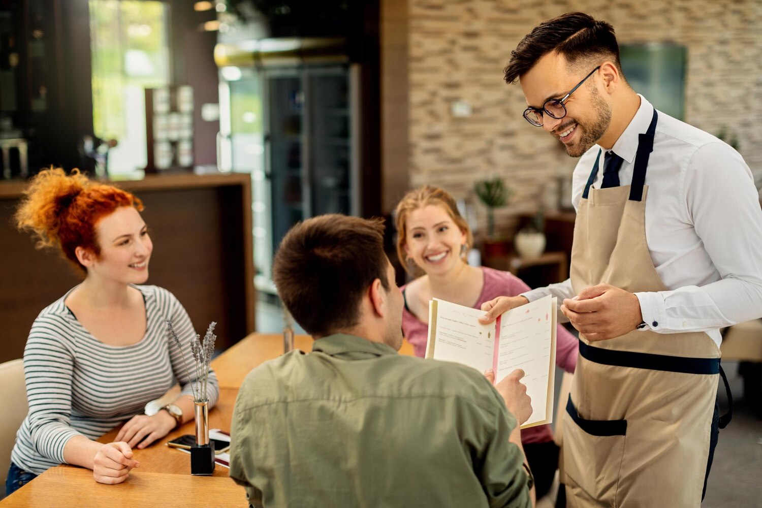 Camarero mostrando la carta a los clientes en un restaurante moderno